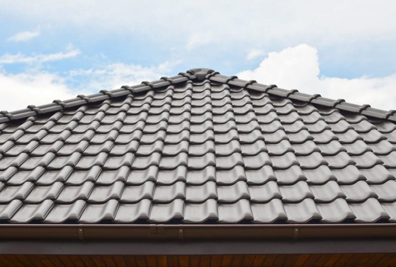 Dark brown ceramic tile roof against blue sky.