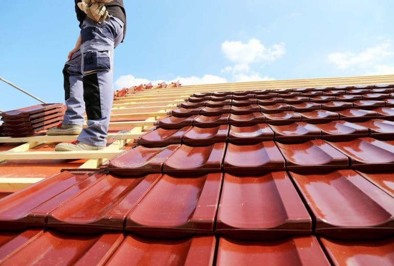 A male contractor applying tiles to roof