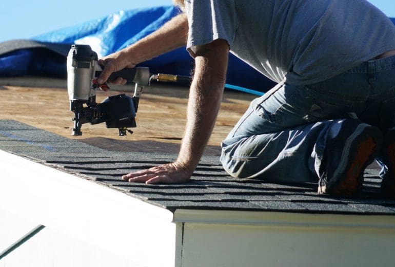 handyman using nail gun to install shingle to repair roof