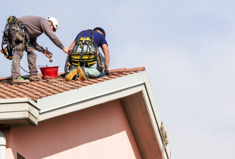 two bricklayers carry out maintenance on the roof
