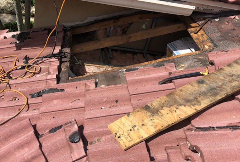 A damaged tile roof that is being repaired by roofing contractors