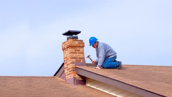 expert roofer with blue hardhat repairing roof