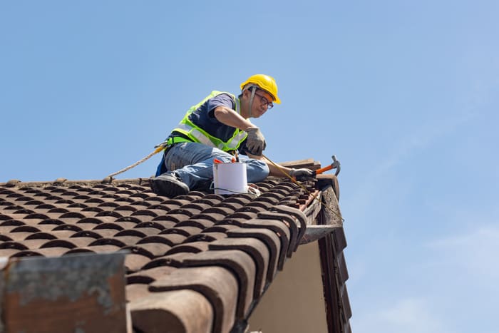 Roofing contractor repairing tile of the old roof..