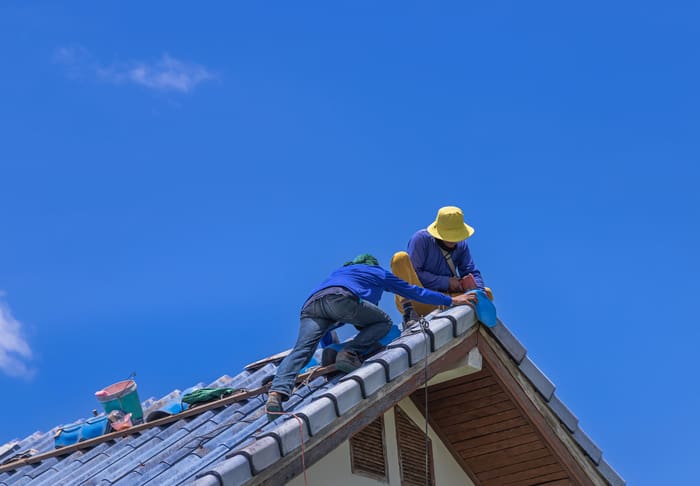 Workers Repairman repairing leaking ridges tile roofing and replace cracked broken tile roofing