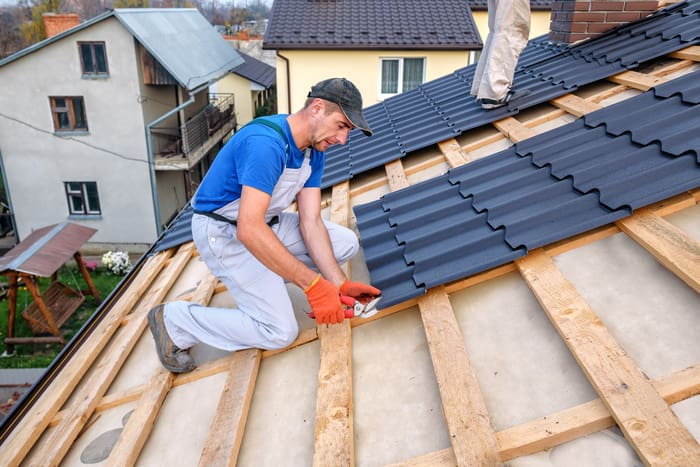 a professional master (roofer) with electric screwdriver covers repairs the roof